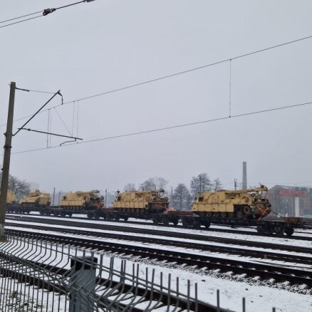 Foto: Aculiecinieks Rīgā uz dzelzceļa novēro bruņumašīnas 'Bradley'