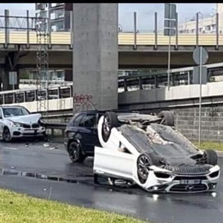 Foto: Pēc sadursmes ar BMW mersedess apgāzies uz jumta